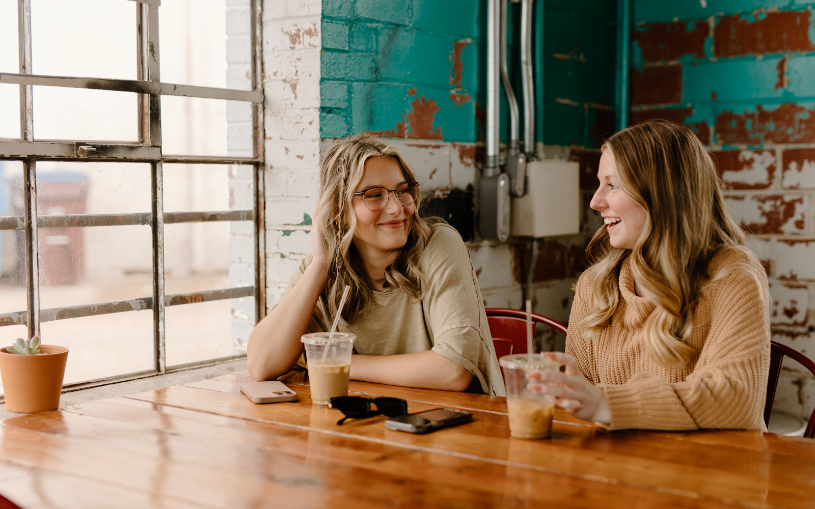 Two people having a warm, friendly conversation over coffee by a sunny window, representing a calm Noon Care enquiry conversation