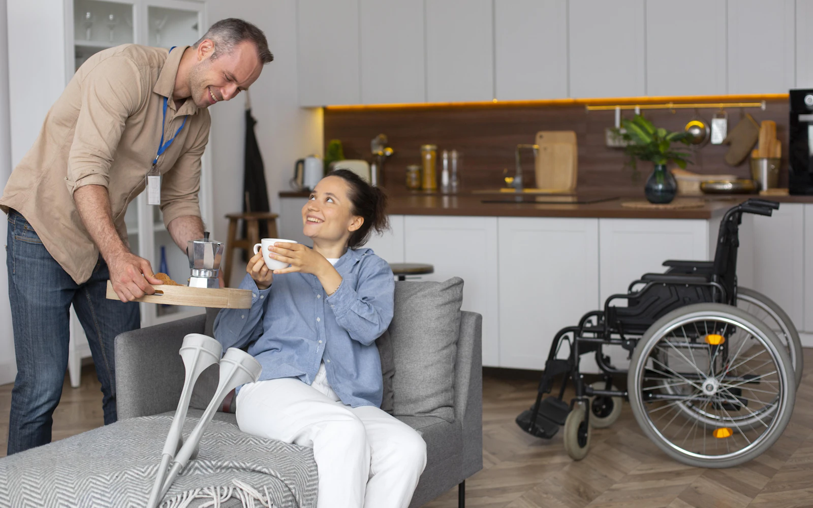 A support worker bringing a morning cuppa to a smiling NDIS participant at home, representing respectful Personal Care support